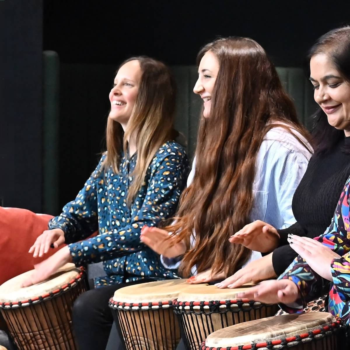 Group of women drumming together on djembes during a community drumming session – Primal Sound