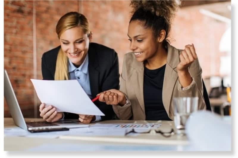 Team Collaboration Showing Focus and Positive Energy Two colleagues reviewing documents together in a bright office, representing teamwork and clear focus.