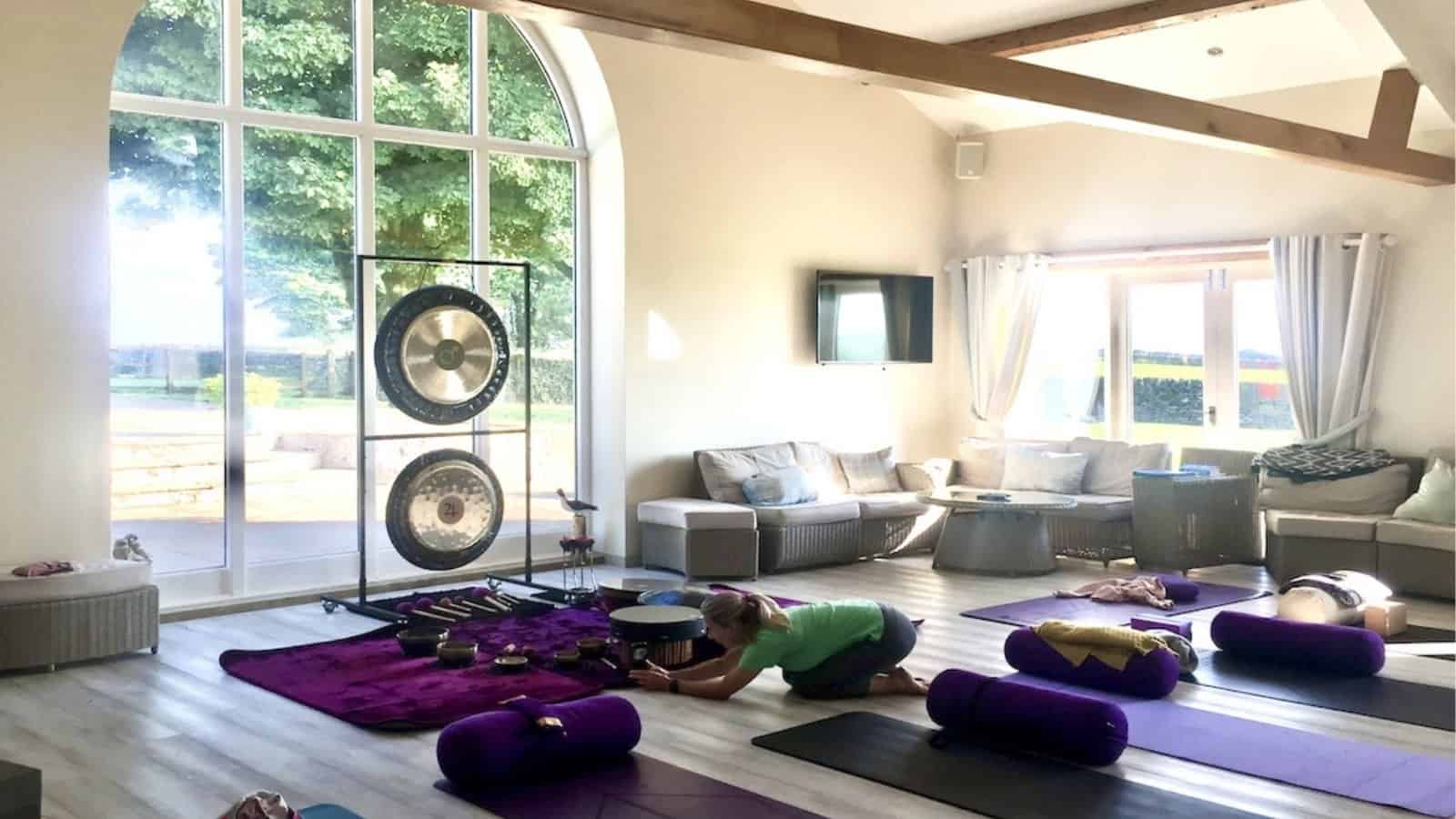 Calm wellbeing space with large arched windows, gongs, yoga mats and relaxation props set up for a restorative session, reflecting the peaceful atmosphere of Primal Sound’s Calm Within programmes.