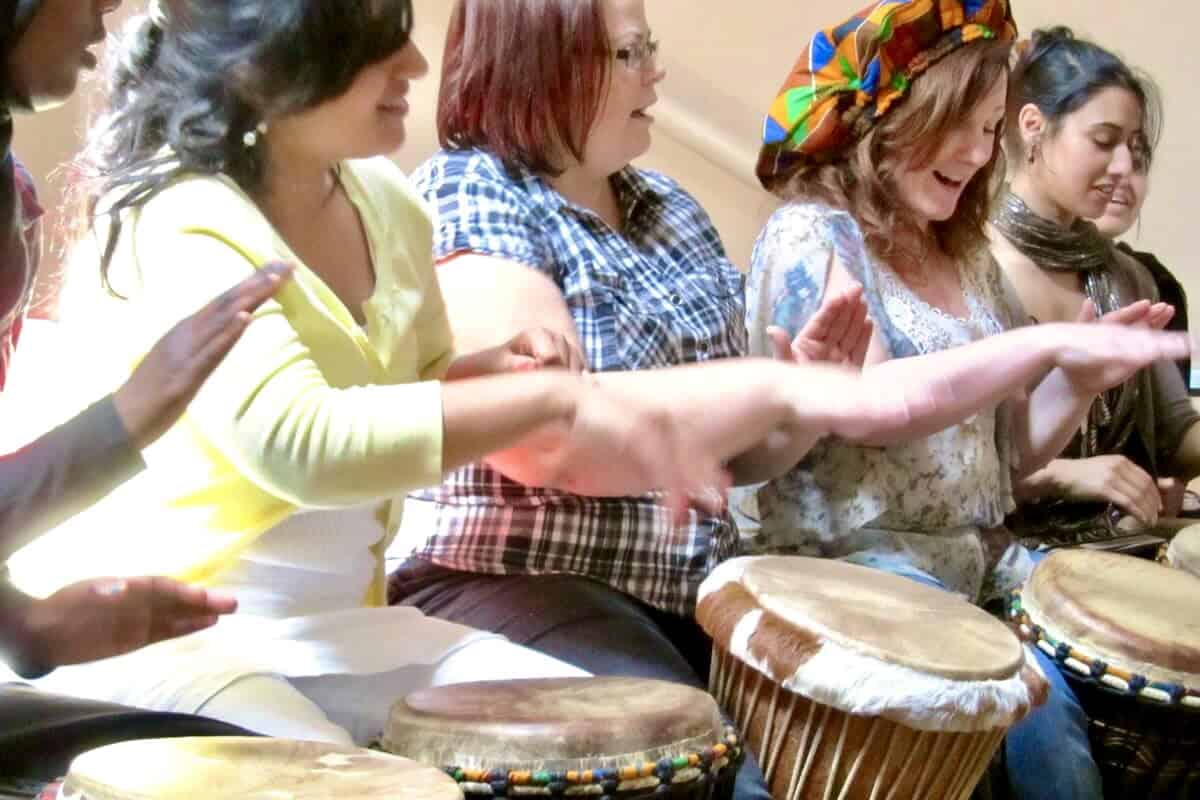 Women drumming together in a lively, joyful community drumming session.